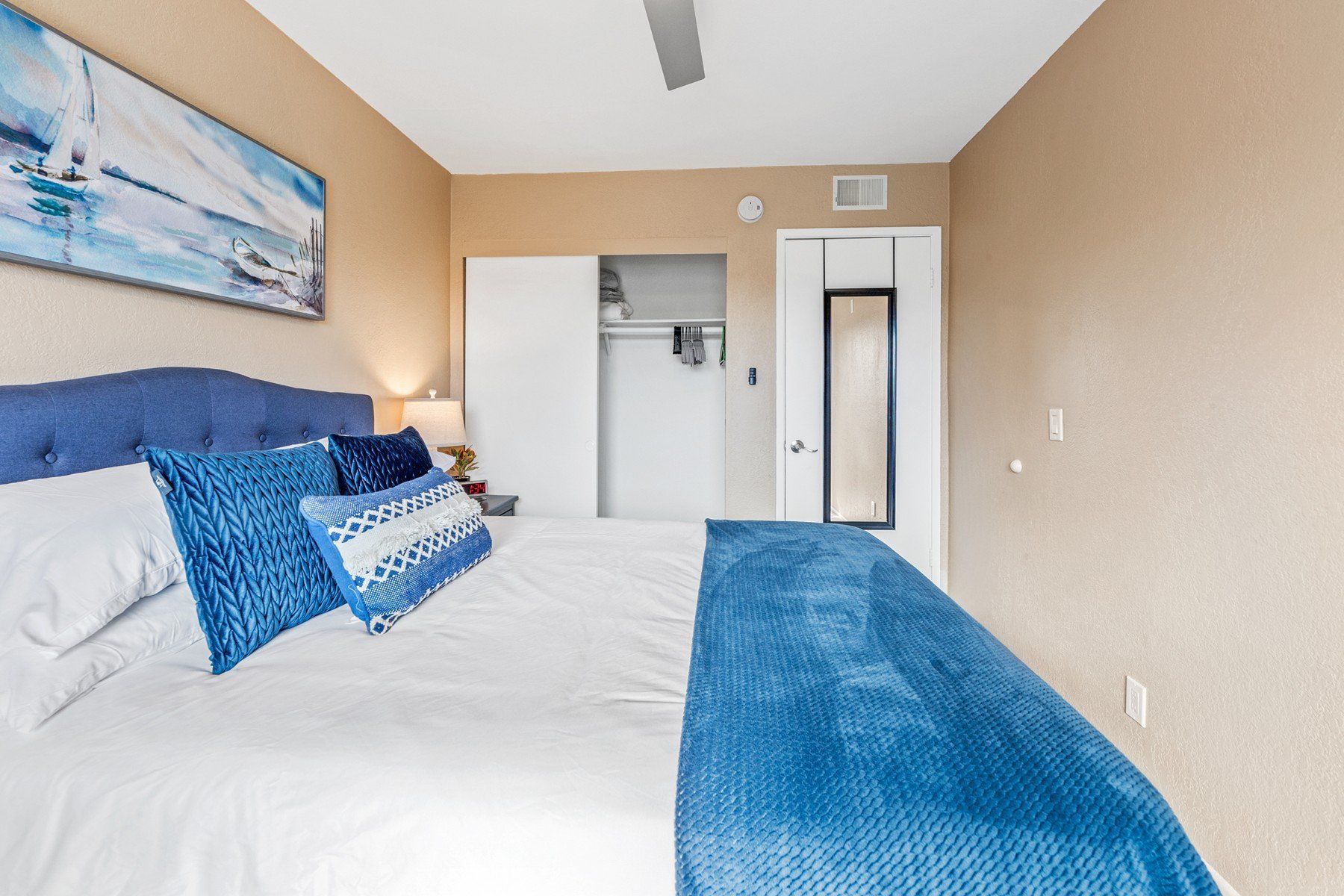 A bedroom with a large bed and a painting on the wall.