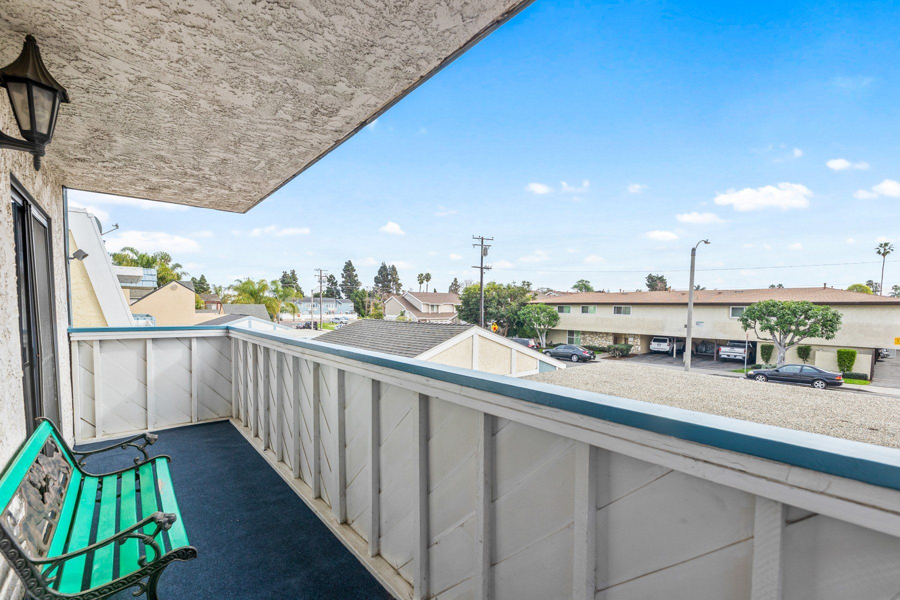 A balcony with a green bench and a view of a city.