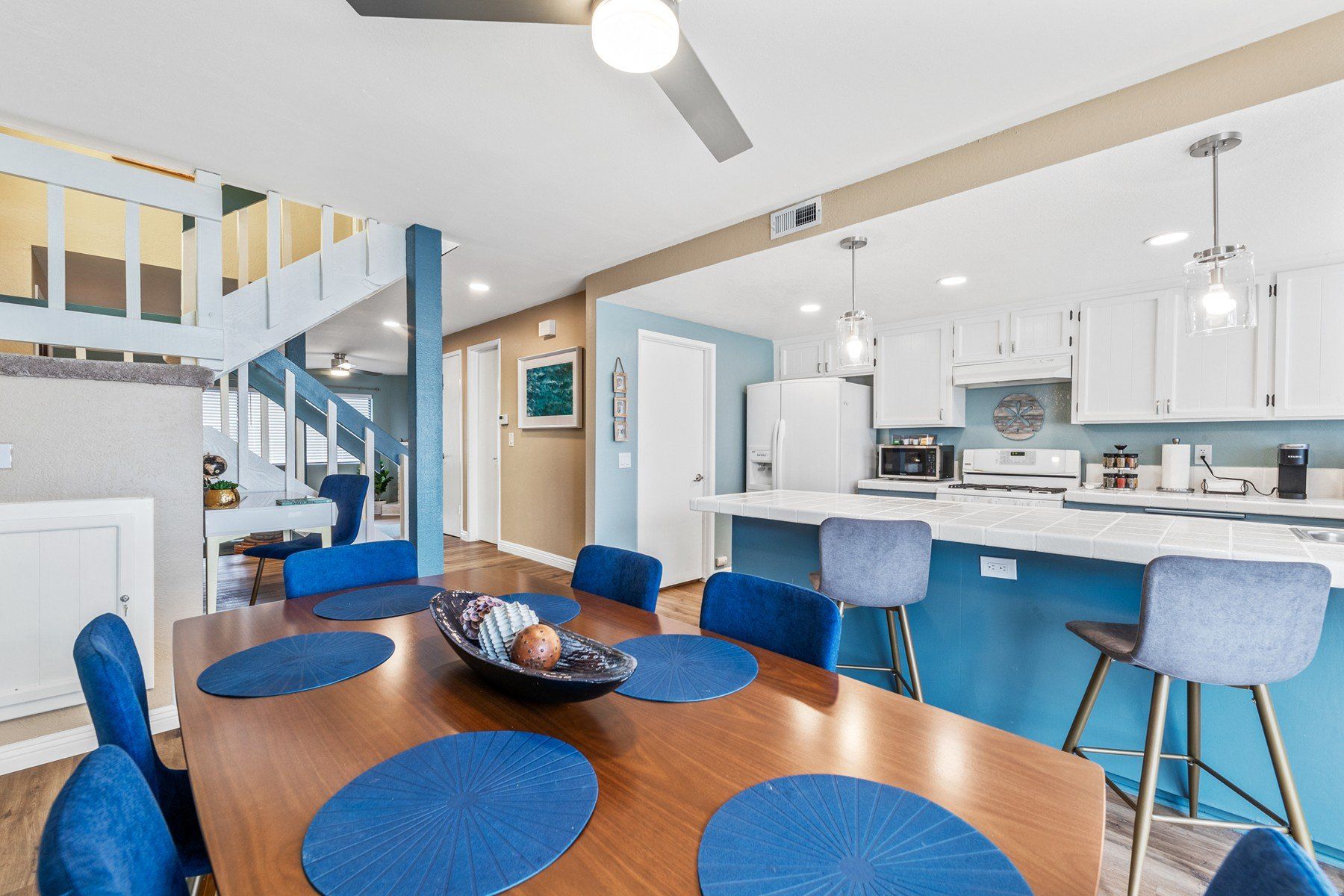 a dining room table with blue place mats and blue chairs in a kitchen .