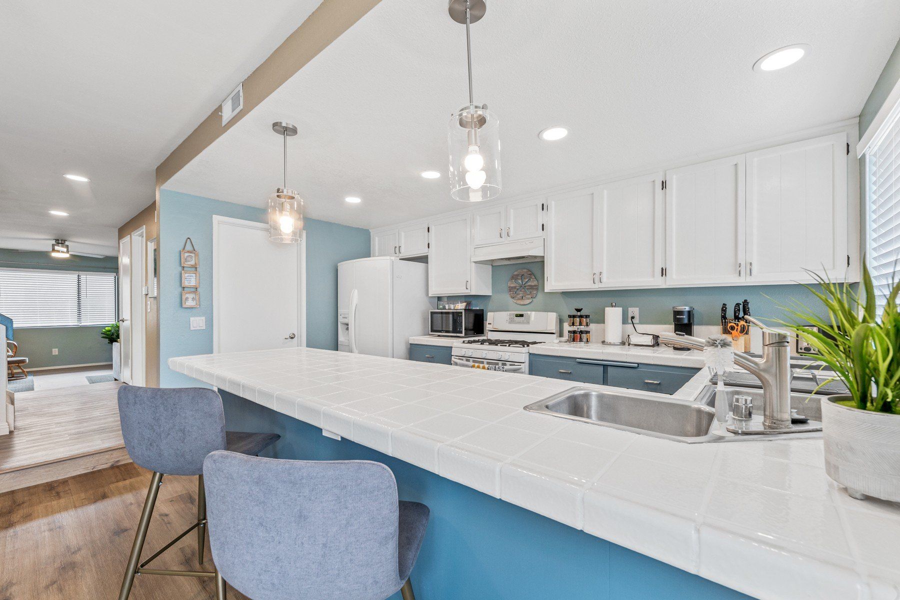 a kitchen with blue cabinets , white cabinets , a sink , and a long counter .