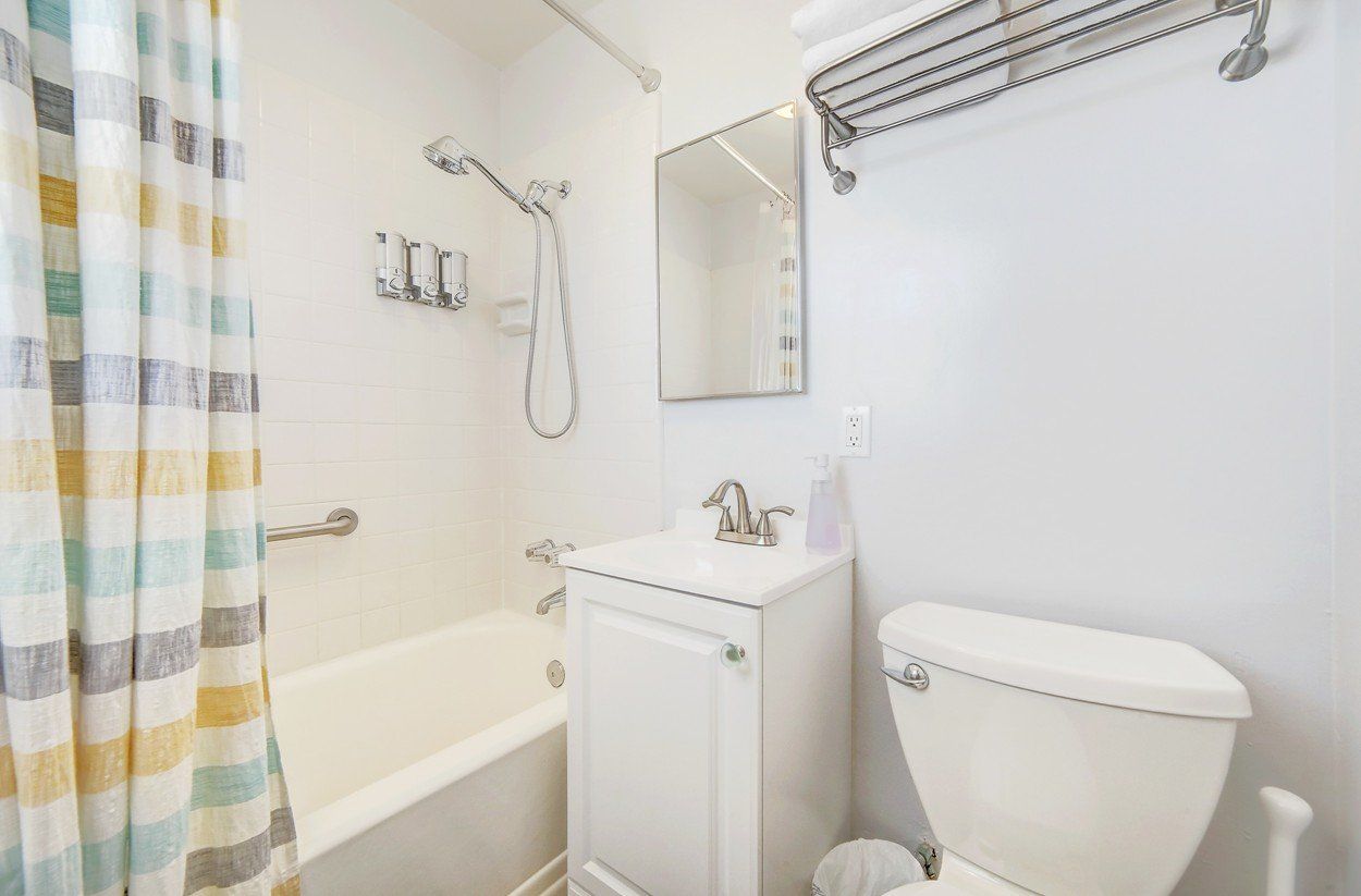 A bathroom with a toilet , sink , bathtub and mirror.