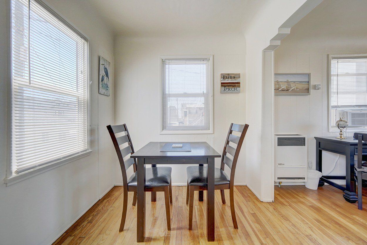 A dining room with a table and chairs and a window.