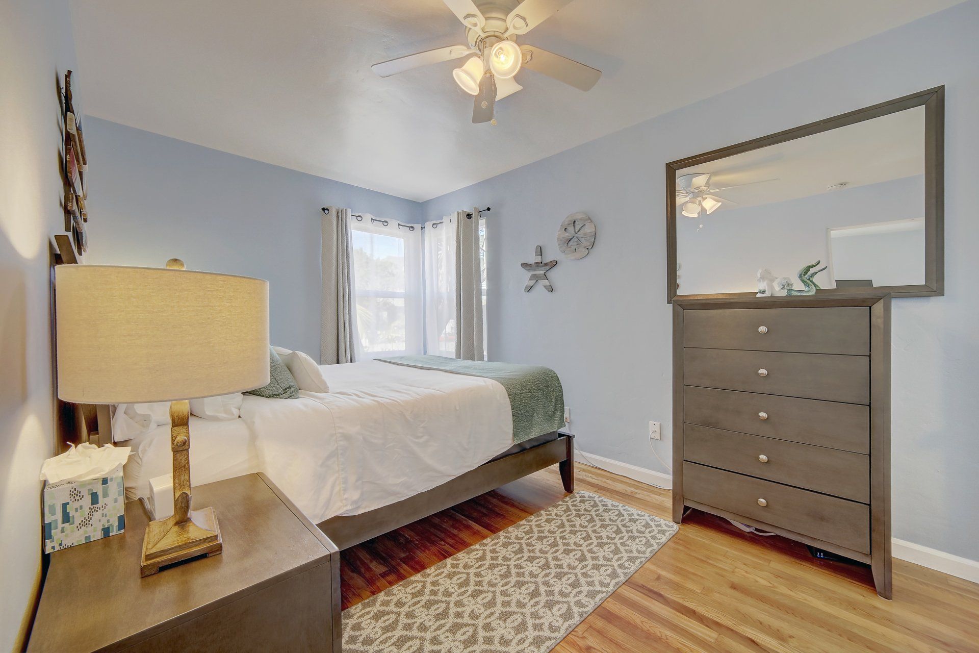 A bedroom with a bed , nightstand , dresser and mirror.