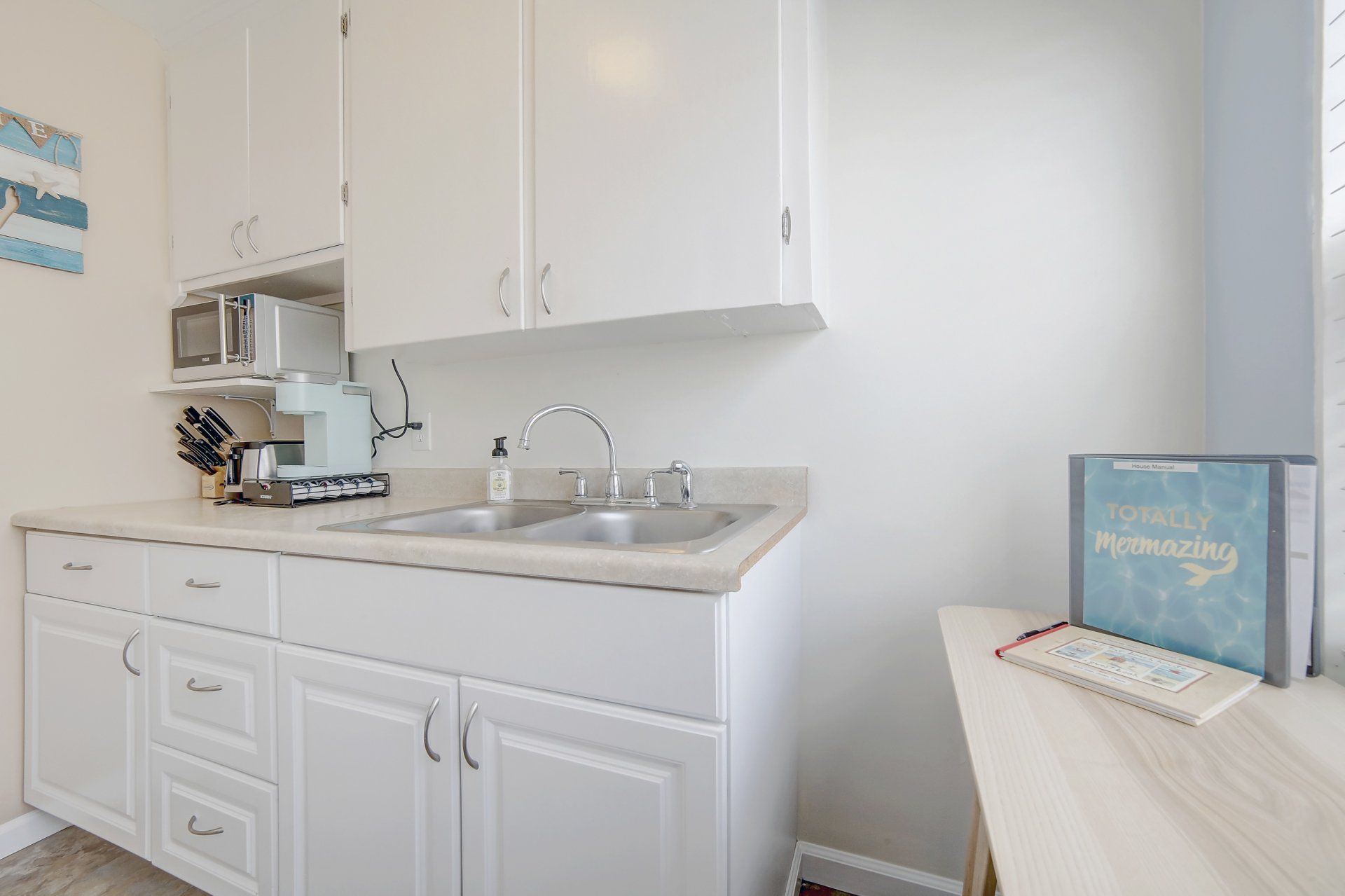 a kitchen with white cabinets , a sink and a microwave .