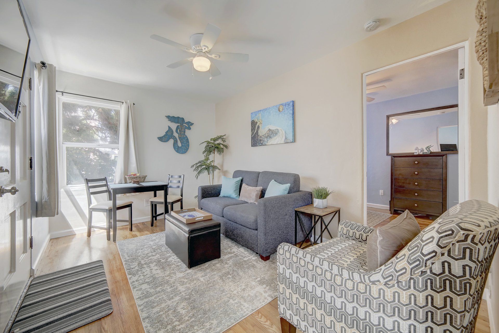 A living room with a couch , chair , table and ceiling fan.