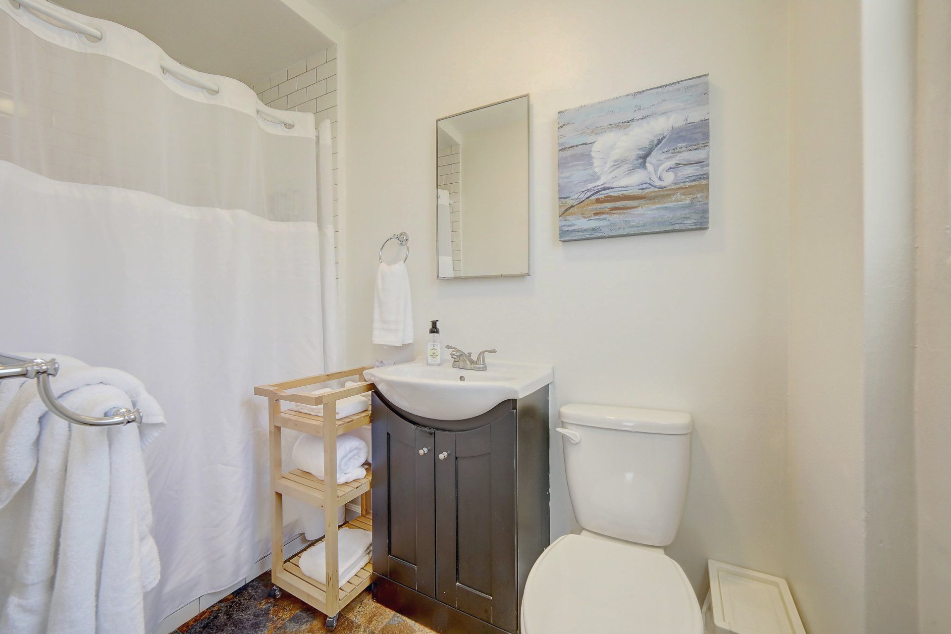 A bathroom with a toilet , sink , mirror and shower curtain.