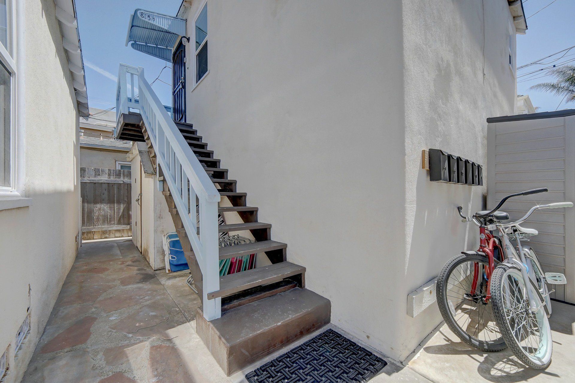 A bicycle is parked on the side of a building next to stairs.