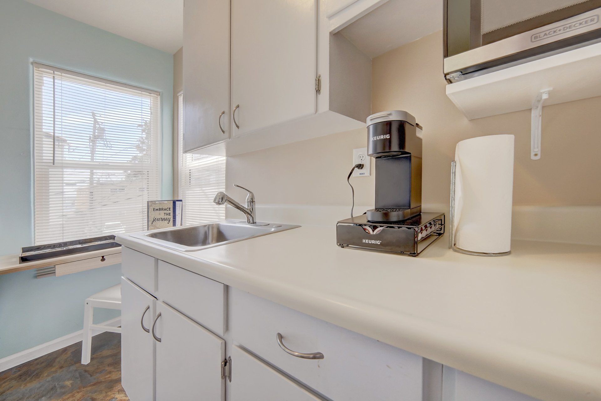 a kitchen with a sink , microwave , coffee maker and paper towels .