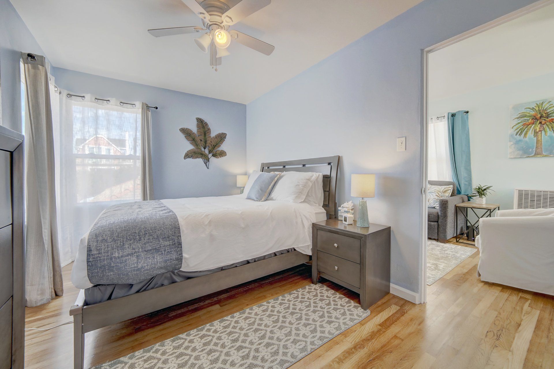 A bedroom with a bed , nightstand , dresser and ceiling fan.