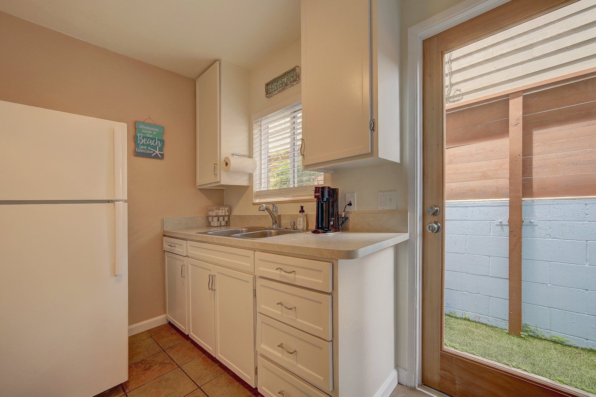 A kitchen with a refrigerator , sink , dishwasher and sliding glass door.