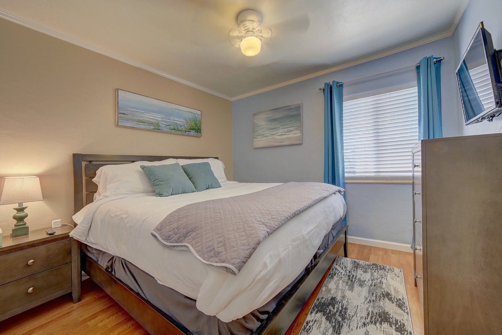 a bedroom with a king size bed , nightstand , dresser and window .