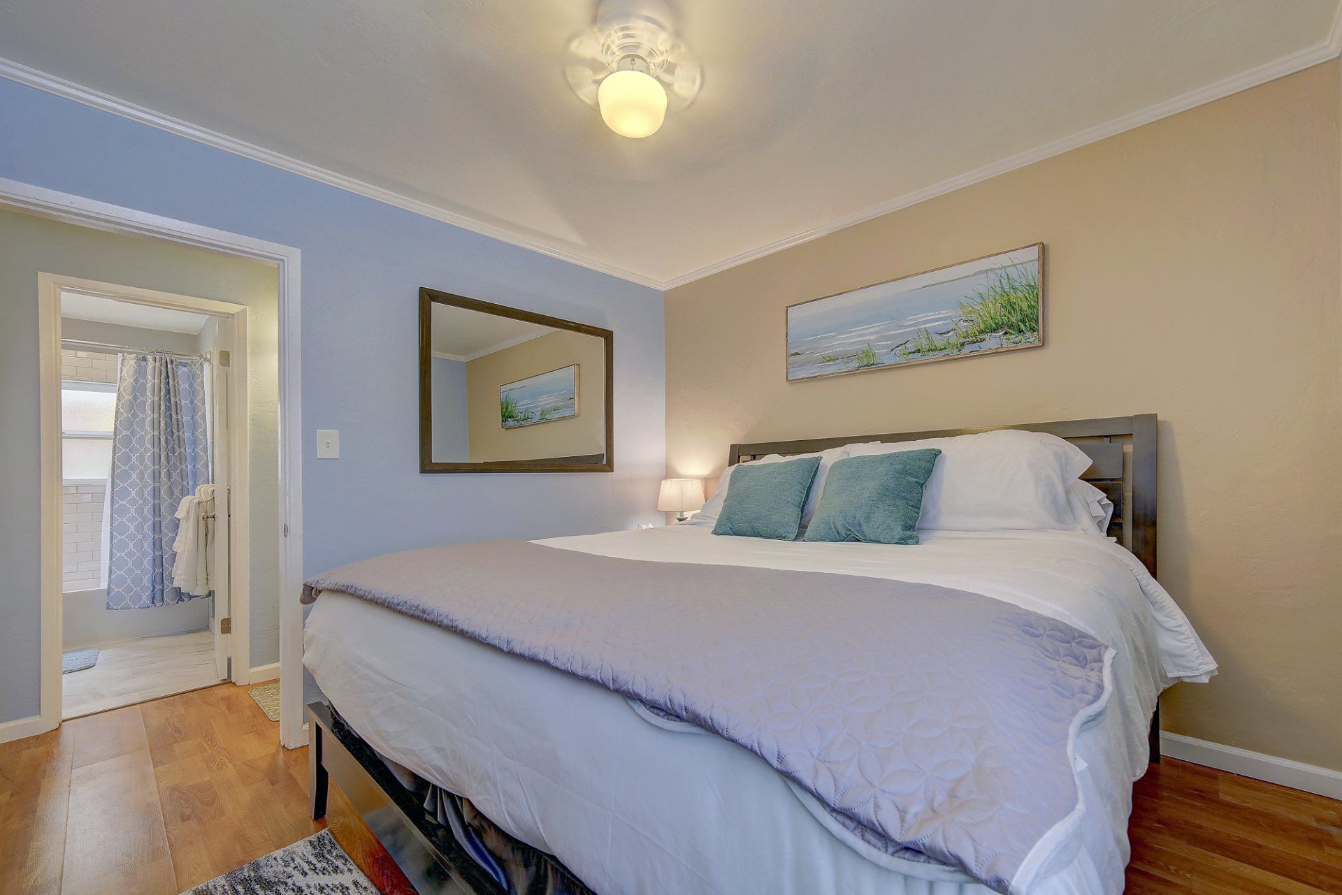 a bedroom with a king size bed , a mirror and a ceiling fan .