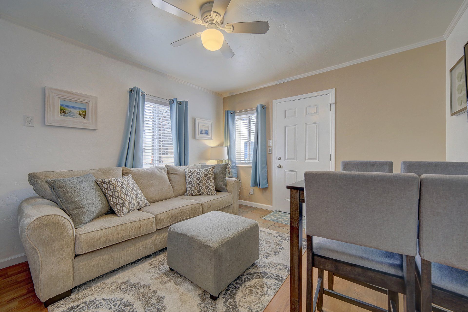 a living room with a couch , ottoman , table and chairs and a ceiling fan .