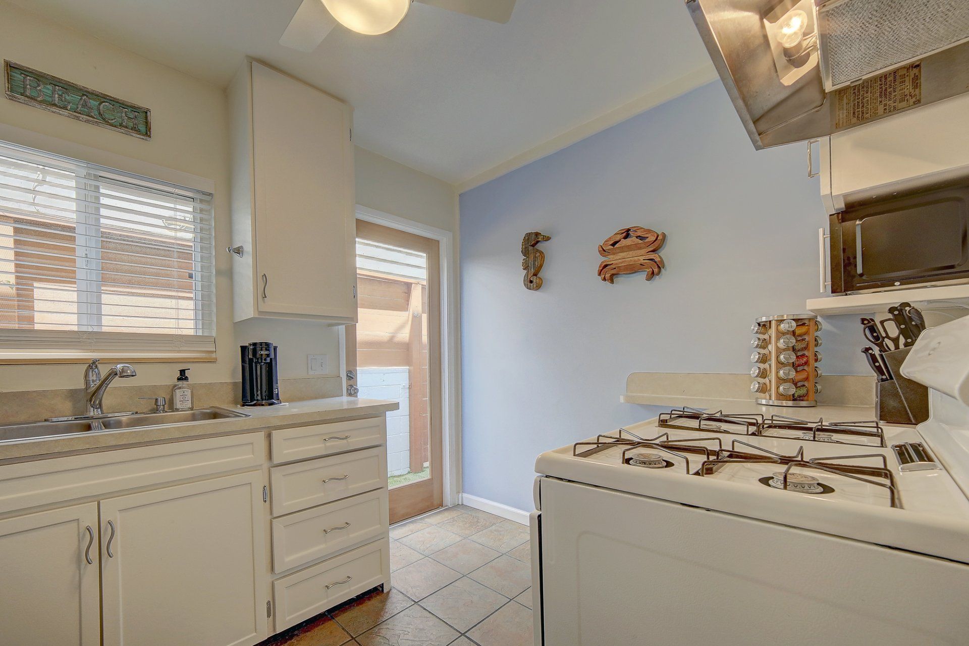 A kitchen with white cabinets , a stove and a sink.