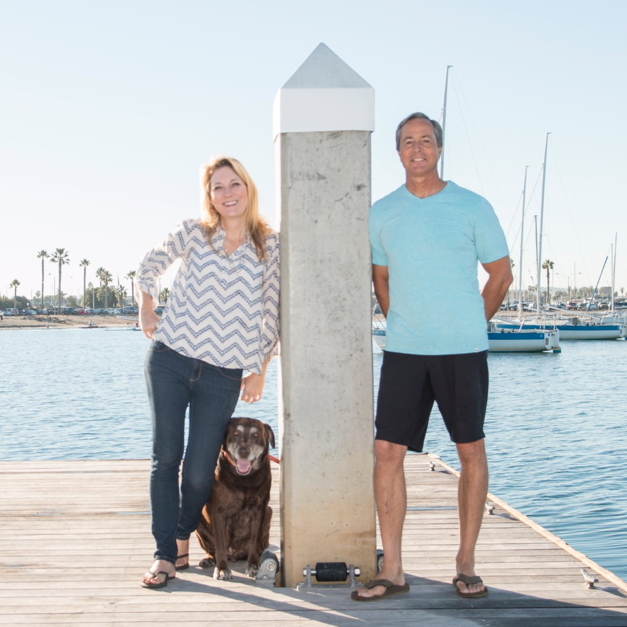 a man and a woman standing next to a dog on a dock
