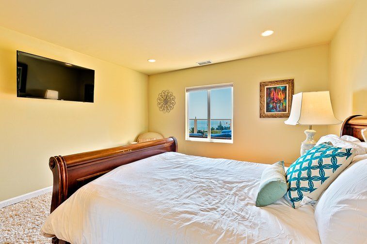 A bedroom with a large bed and a flat screen tv on the wall.