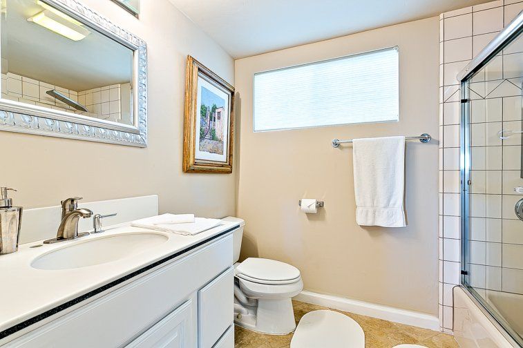 A bathroom with a toilet , sink , mirror and shower.