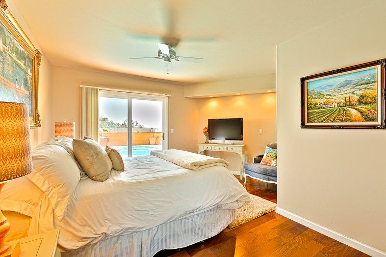 A bedroom with a king size bed , television , and a painting on the wall.