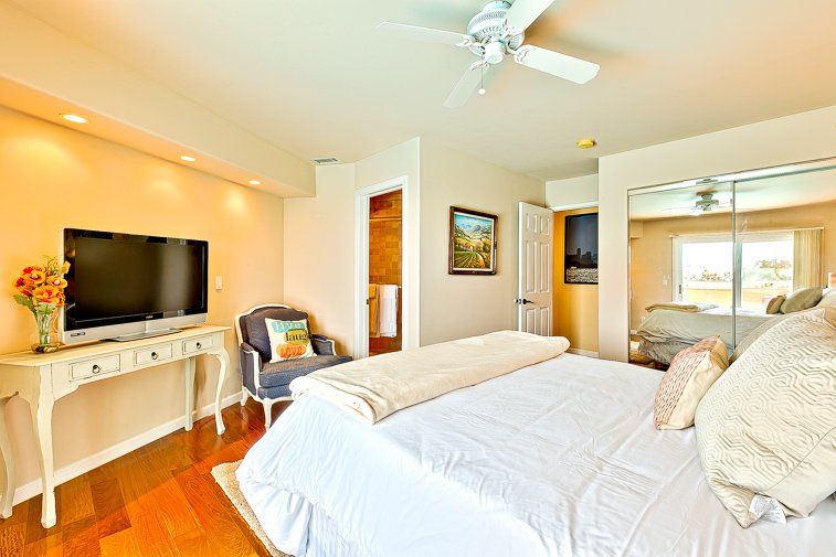 A bedroom with a king size bed , television , chair and ceiling fan.