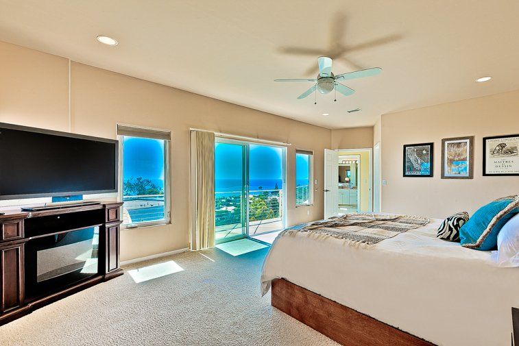 A bedroom with a king size bed , television , fireplace and sliding glass doors.