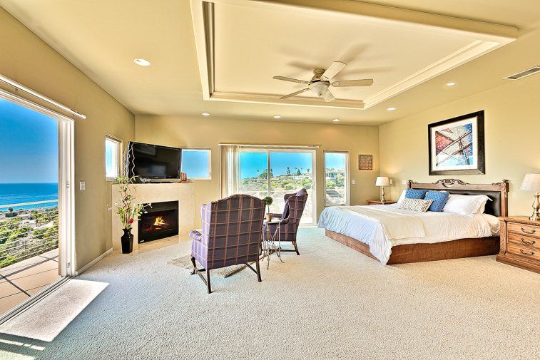 A large bedroom with a king size bed , chairs , a fireplace and a view of the ocean.