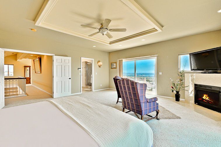 A large bedroom with a fireplace and a ceiling fan.