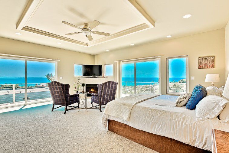 There is a large bed in the middle of the room with a view of the ocean.