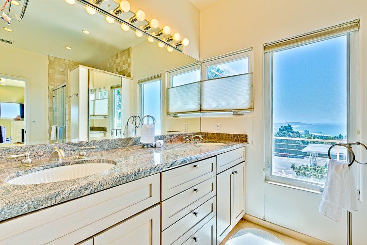 A bathroom with two sinks , a mirror and a window.