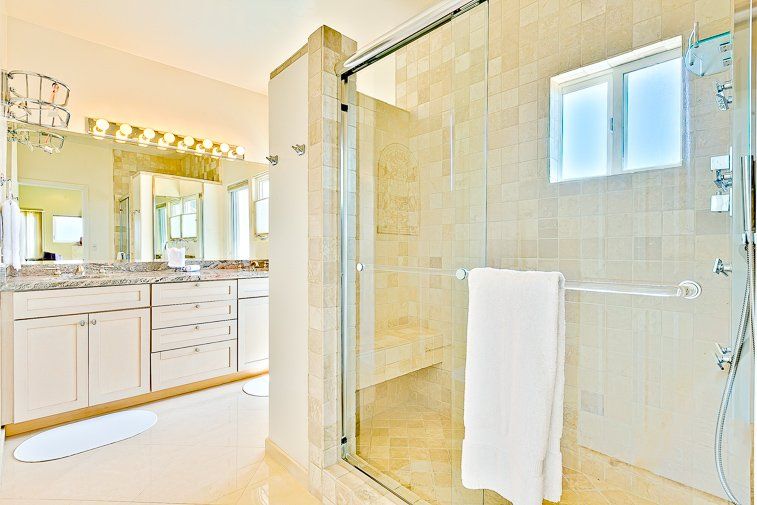 A bathroom with two sinks and a walk in shower.