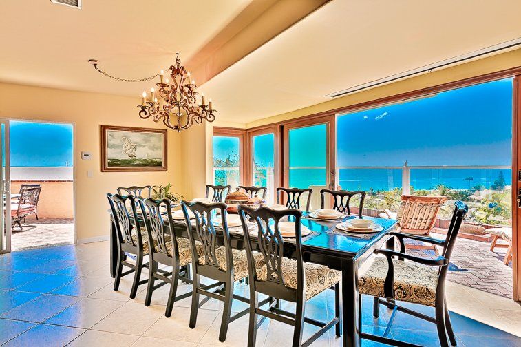 A dining room with a long table and chairs and a chandelier.