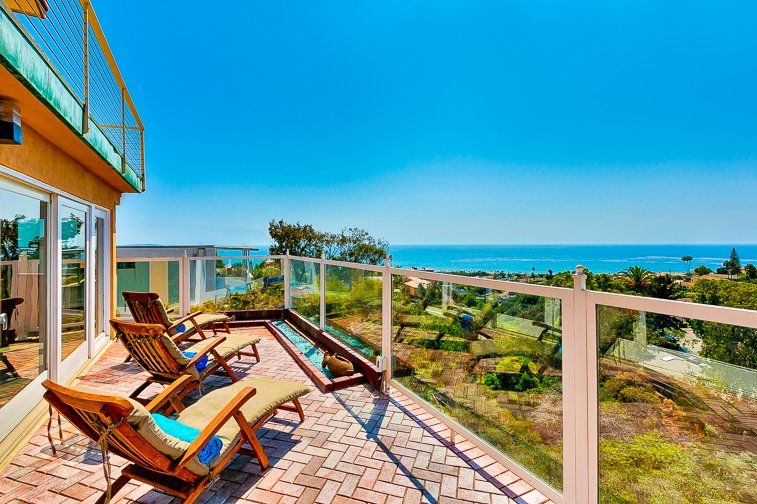 A balcony with chairs and a view of the ocean.