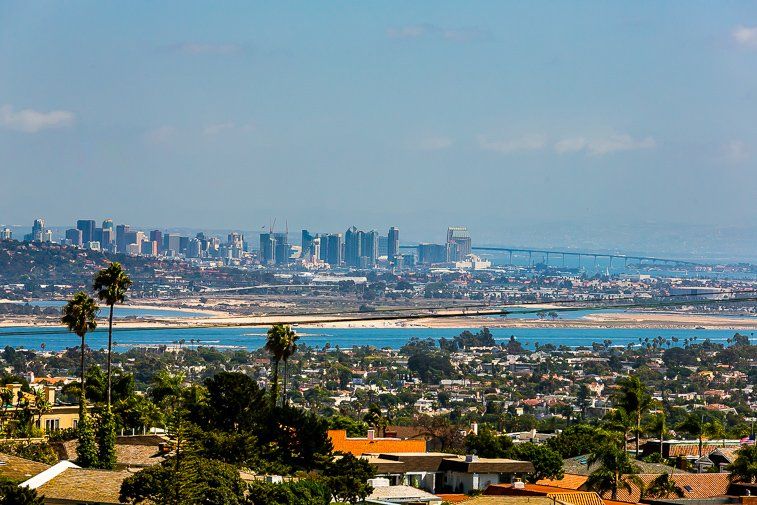 An aerial view of a city with a body of water in the foreground and a city skyline in the background.