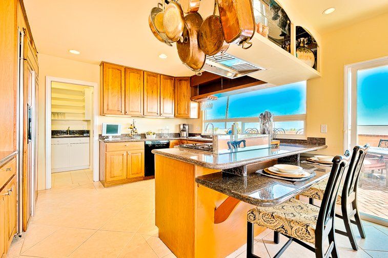 A kitchen with a dining table and chairs and pots hanging from the ceiling.