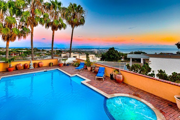 a large swimming pool with a view of the ocean and palm trees