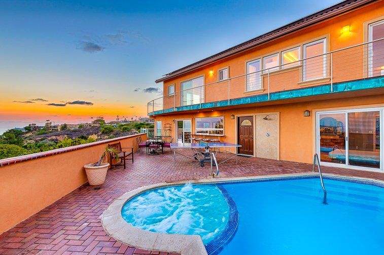 a large house with a swimming pool and a hot tub in front of it .