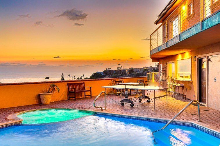 a large swimming pool with a ping pong table in front of a house at sunset .