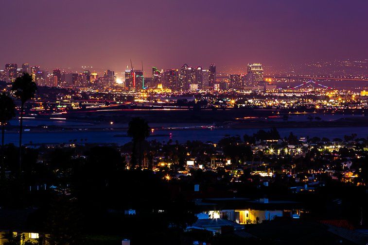 A city skyline at night with a purple sky in the background