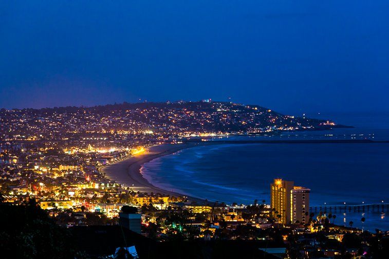 An aerial view of a city at night with a beach in the foreground.