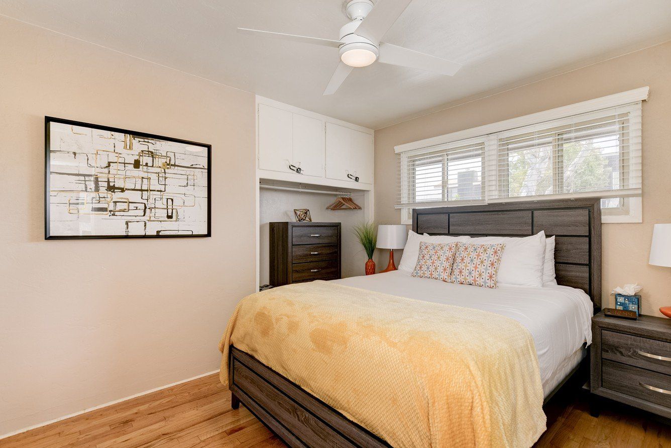 a bedroom with a bed , nightstand , dresser and ceiling fan .