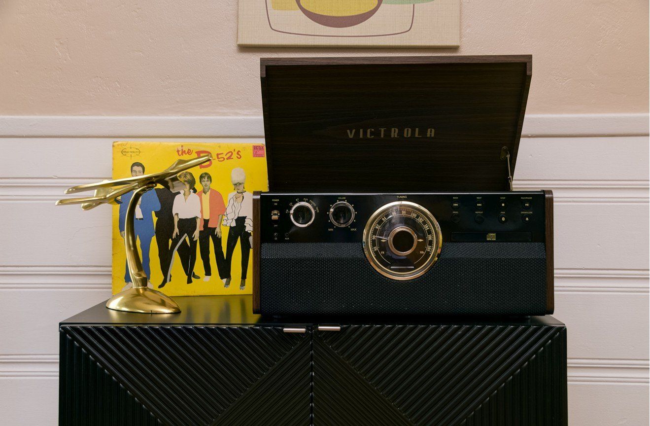 A victoria record player is sitting on top of a black dresser.