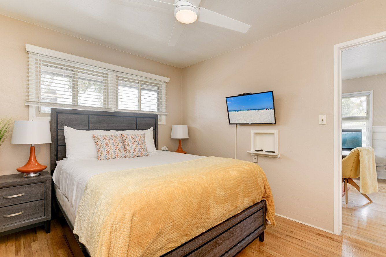 a bedroom with a bed , nightstand , television and ceiling fan .