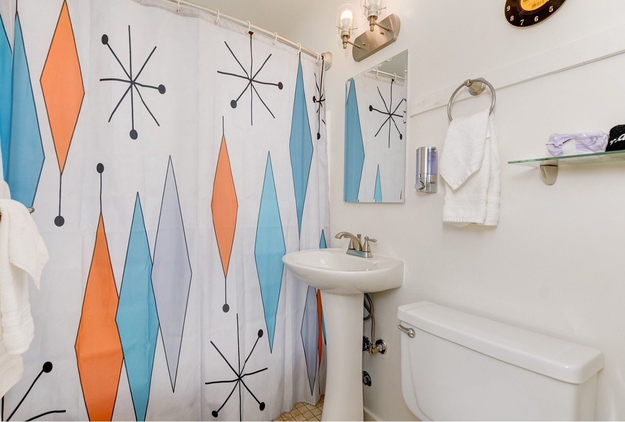 a bathroom with a colorful shower curtain and a sink