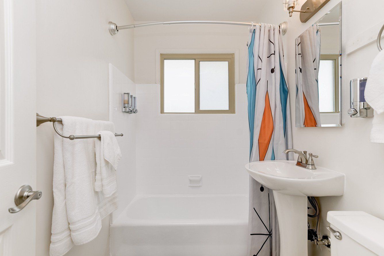 a bathroom with a sink , tub , mirror and window .