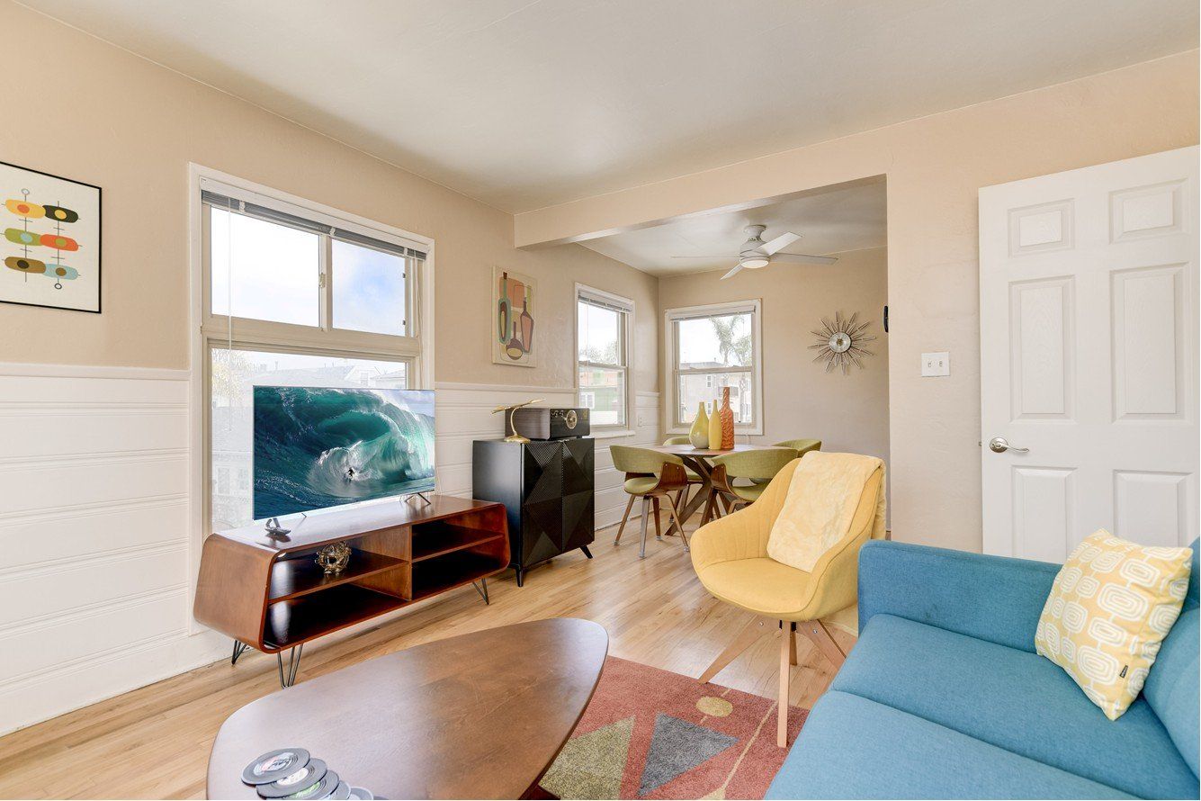 A living room with a blue couch , yellow chair , and a flat screen tv.