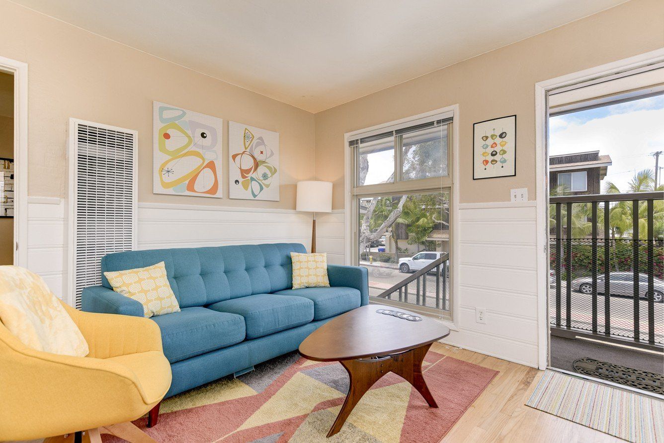 A living room with a blue couch , yellow chair , and coffee table.