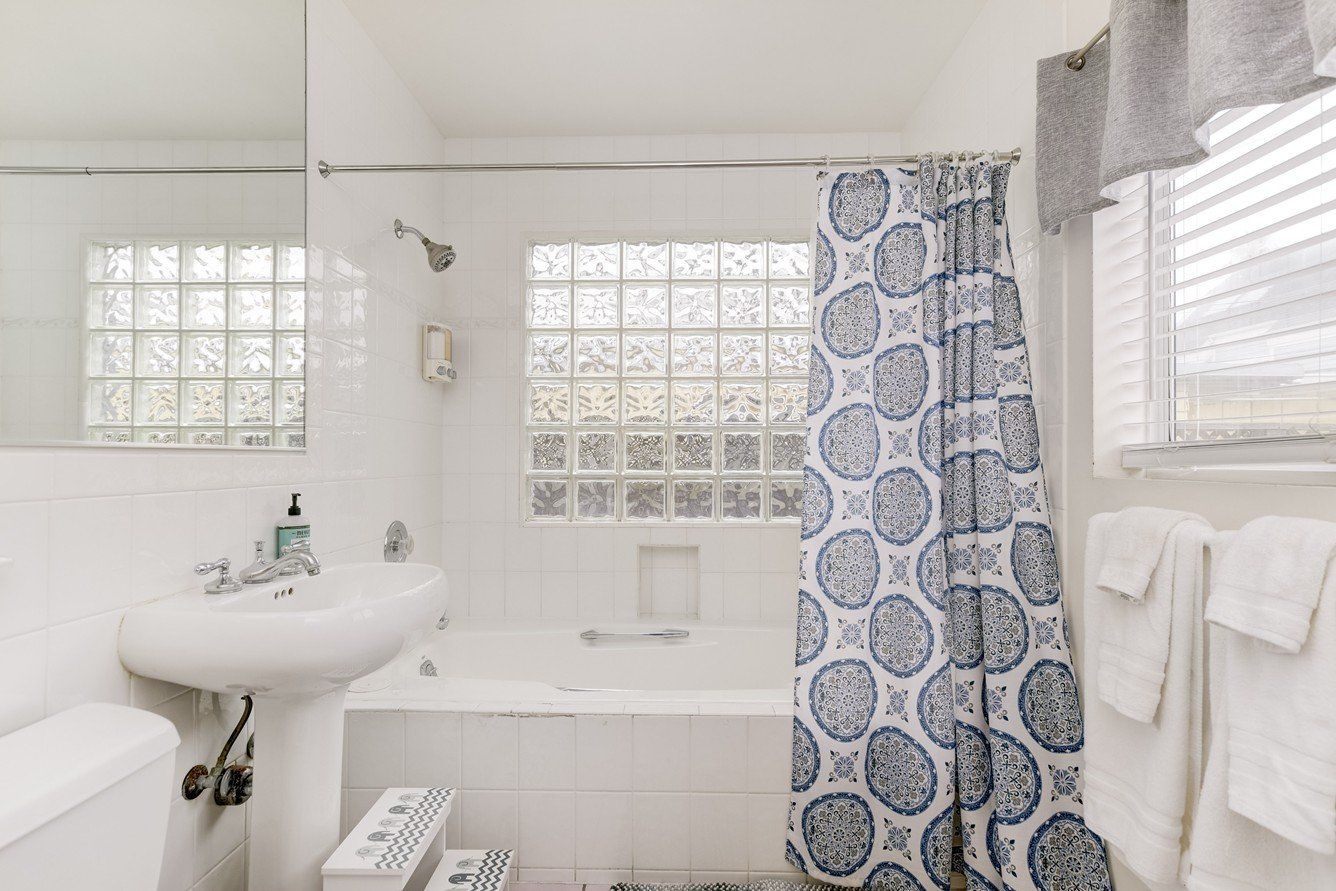 a bathroom with a bathtub , sink , mirror and shower curtain .