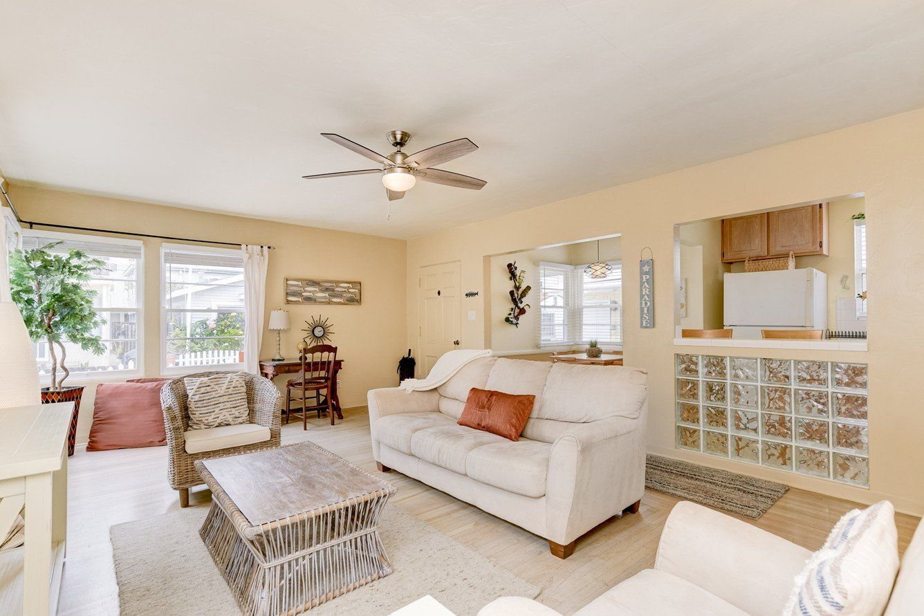 a living room with a couch , chair , coffee table and ceiling fan .