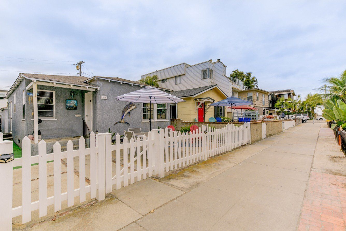 a white picket fence surrounds a row of houses on a sidewalk .