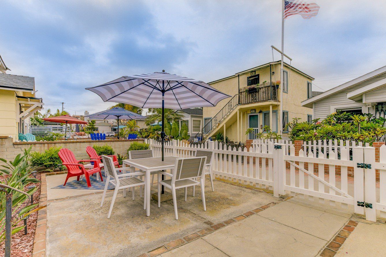 a patio with a table and chairs and umbrellas in front of a house .