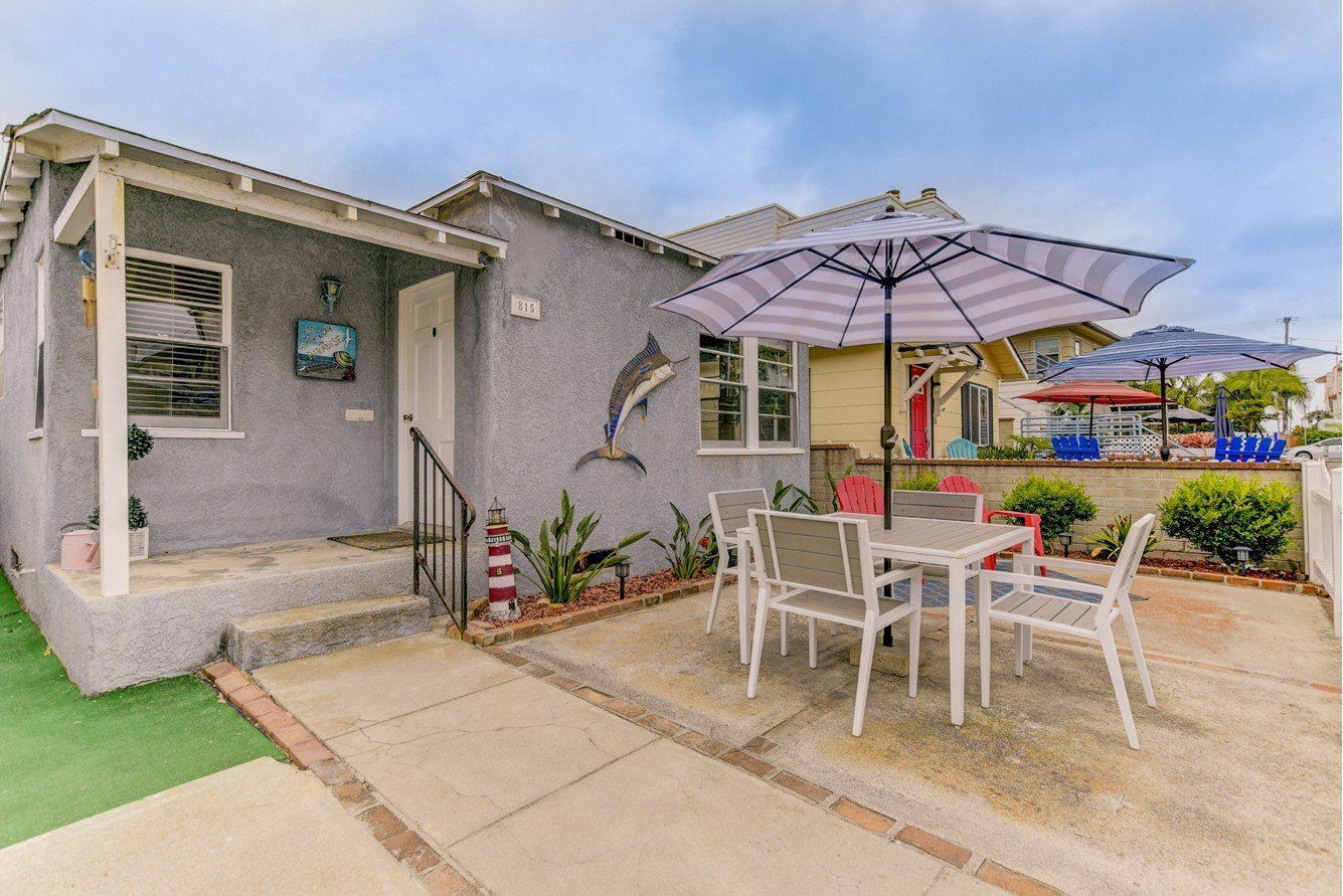 a patio with a table and chairs and an umbrella in front of a house .